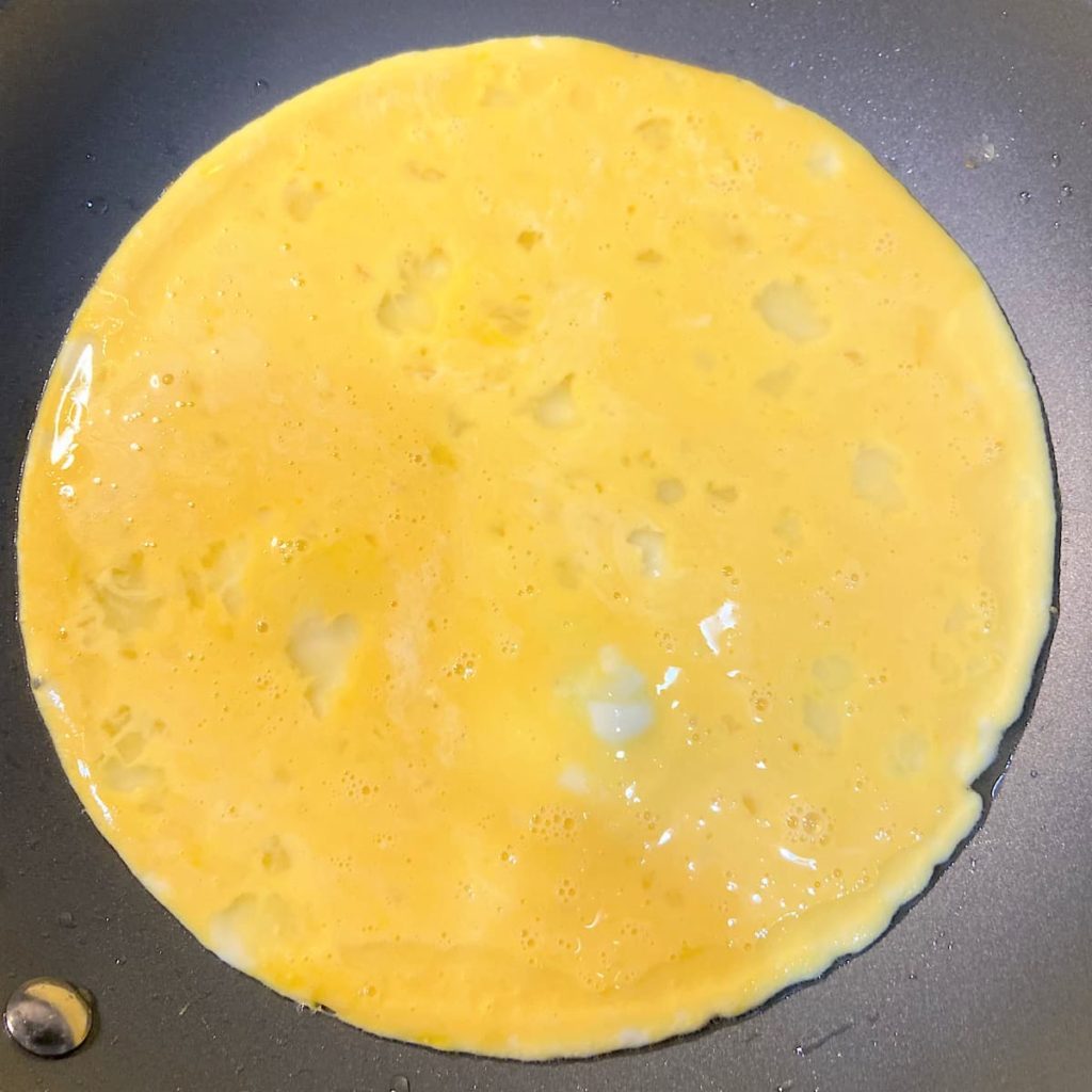whisked eggs in pan for vegetable omelet