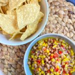 corn and black eyed pea dip in bowl with corn chips