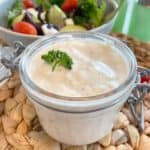 homemade ranch dressing in jar ready to serve on green leafy saladsalad