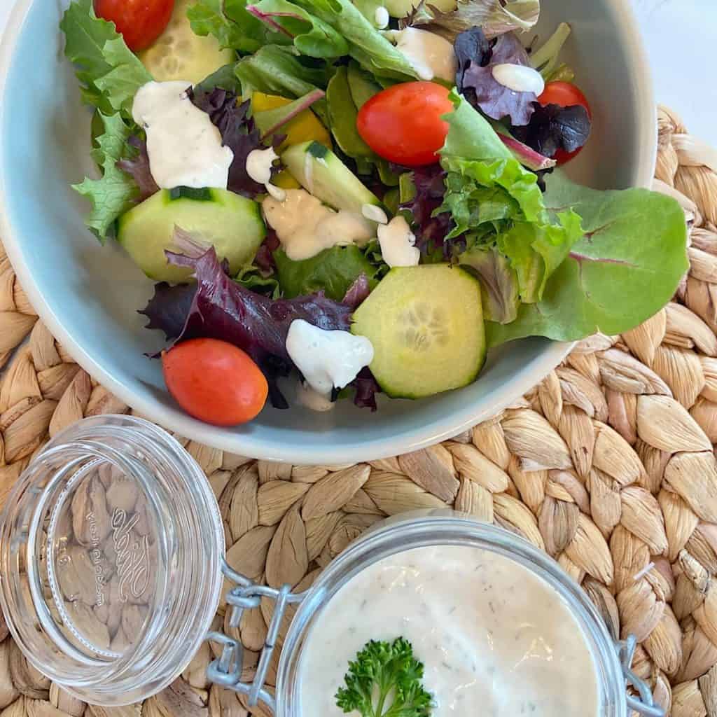 homemade ranch dressing in a jar with bowl of salad