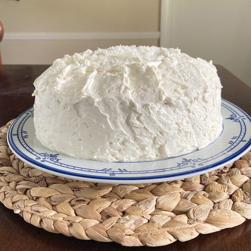 Frosted coconut cake on cake plate.