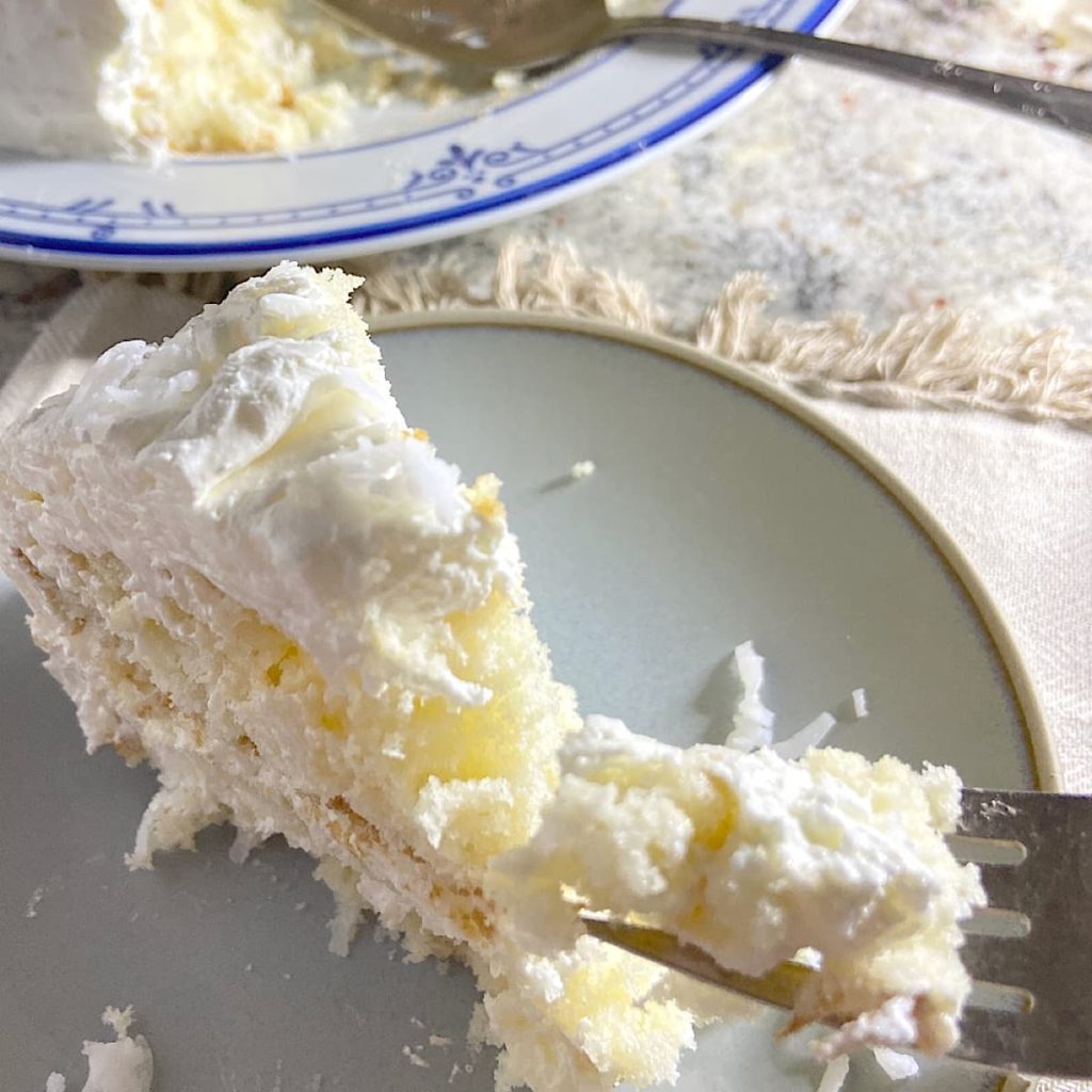 slice of moist coconut refrigerator cake on plate ready to eat
