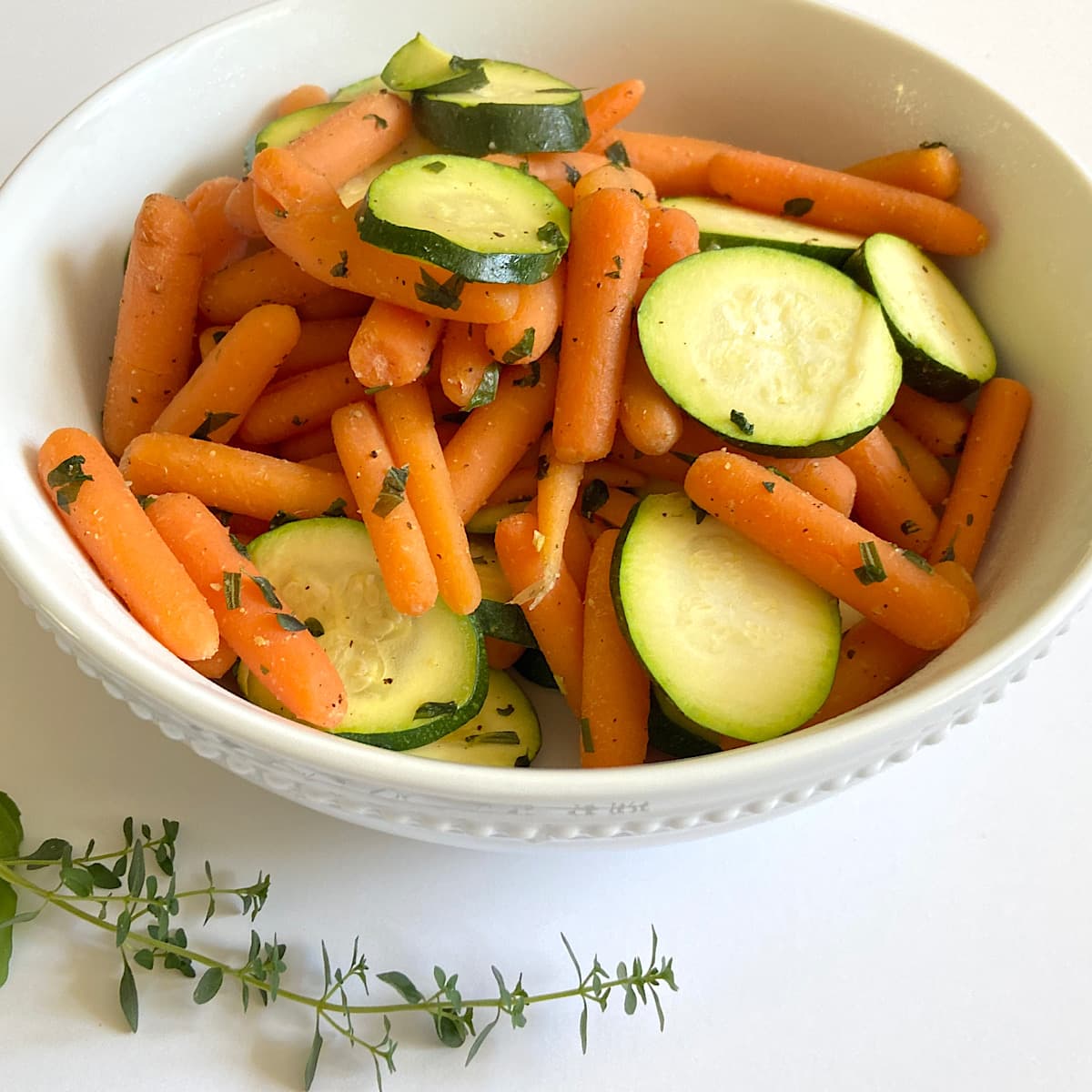 bowl of baby carrots and zucchini seasoned with spices and broth