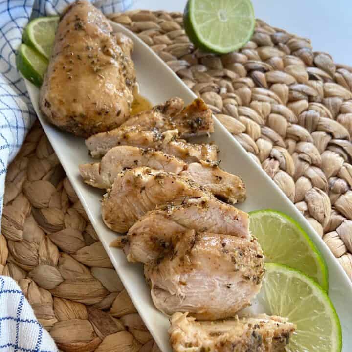 tray of sliced baked chicken with limes