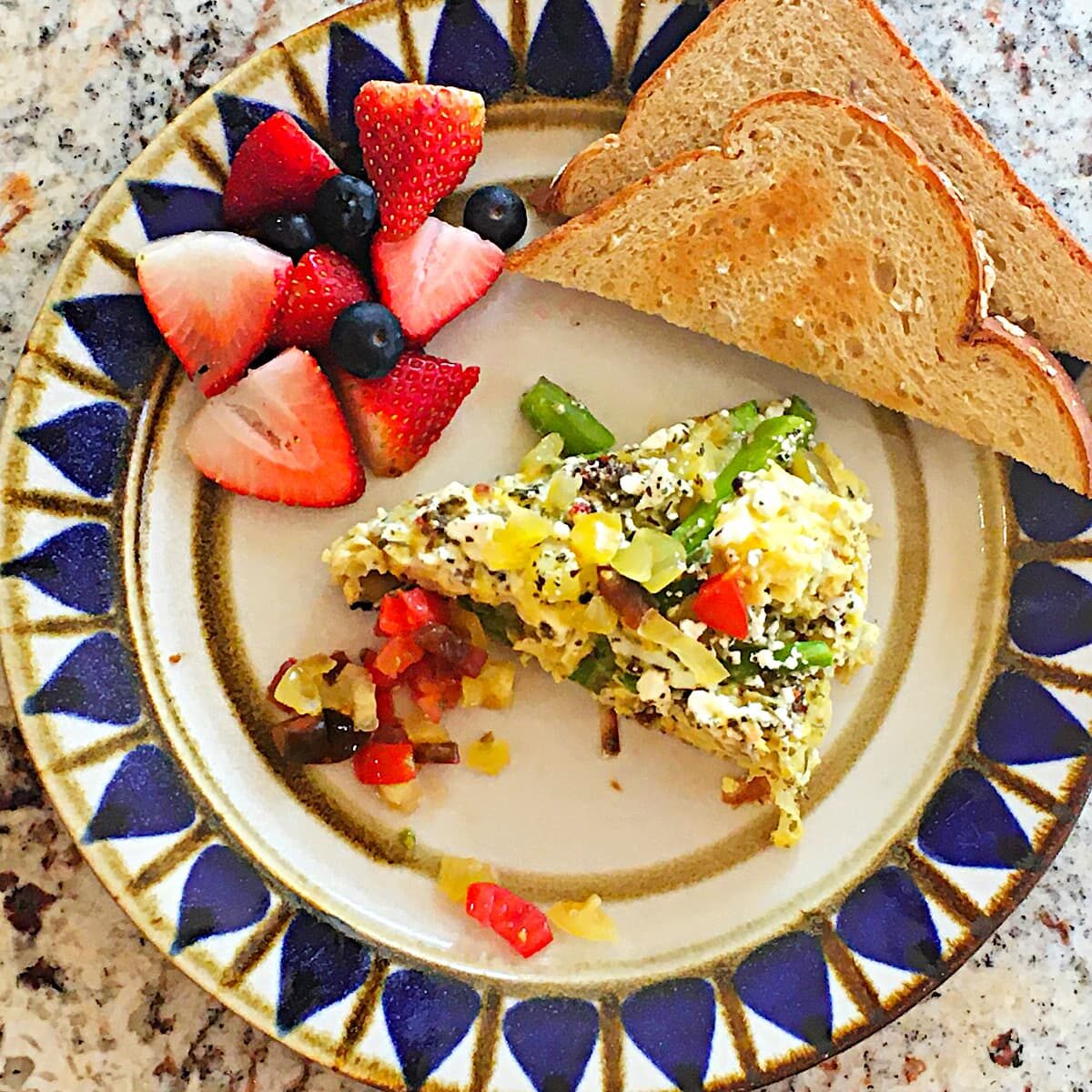asparagus frittata with tomato relish, fresh fruit, and toast on a plate.
