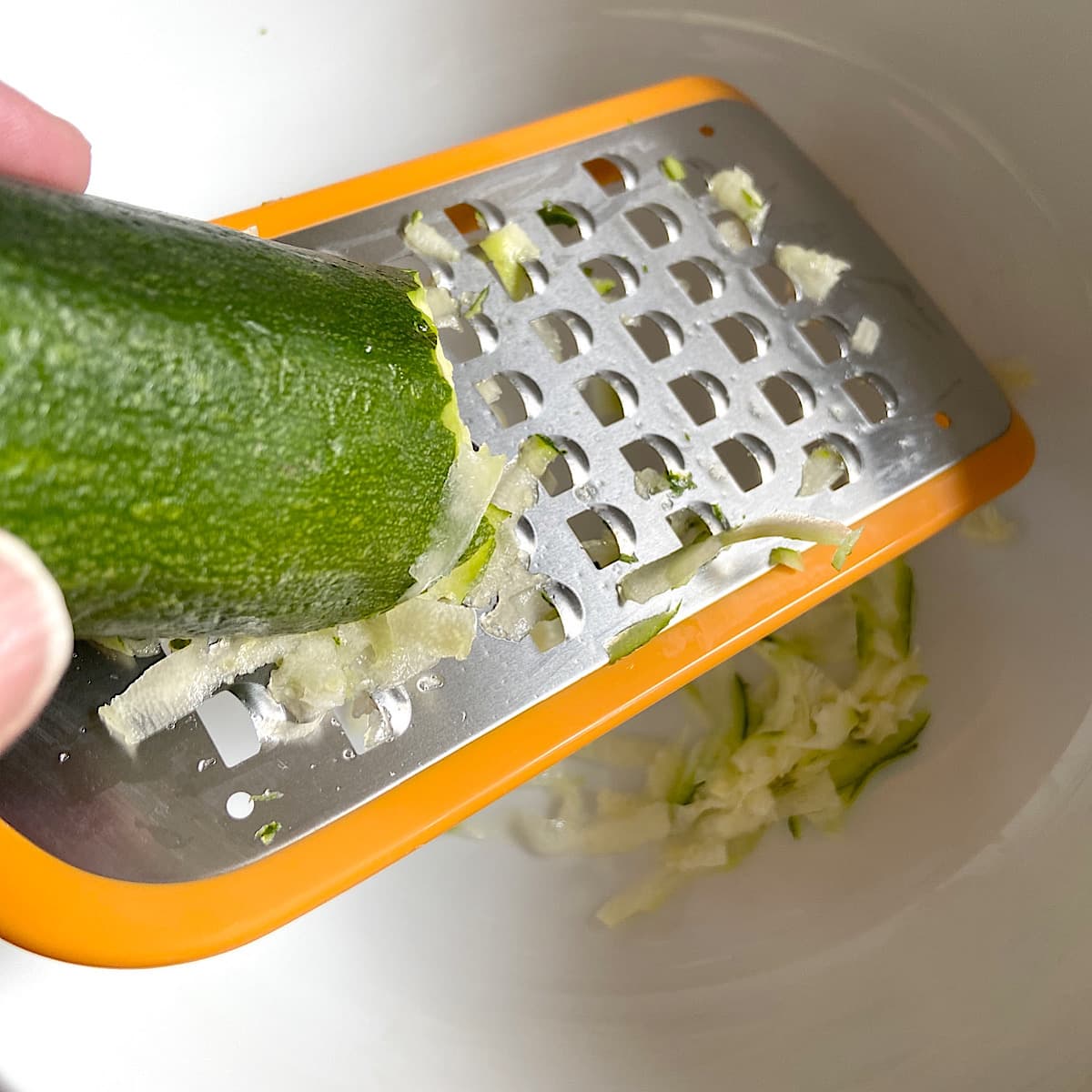 grating zucchini into a bowl