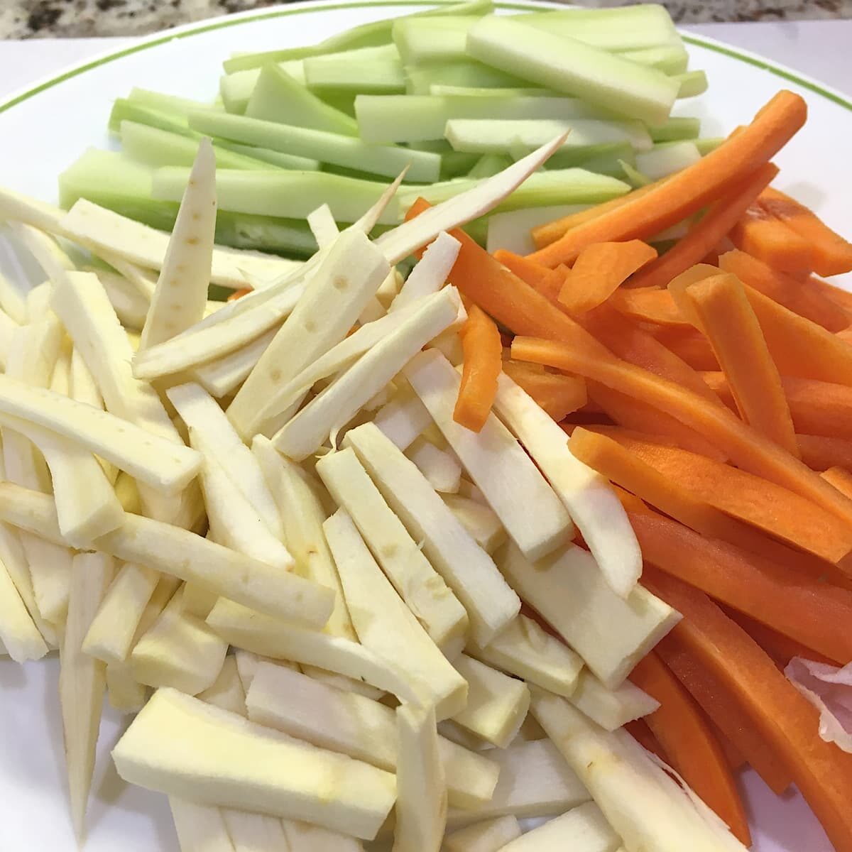 plate of group of julienned carrots, broccoli stems, and parsnips.