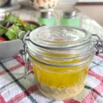 olive oil salad dressing in jar by bowl ofsalad