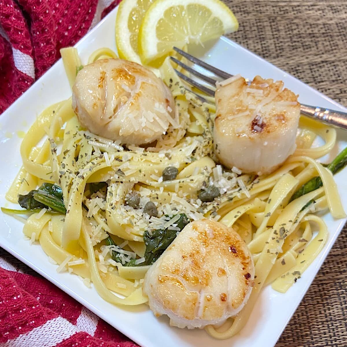 pan-seared scallops with capers, spinach, and fettucine on a plate