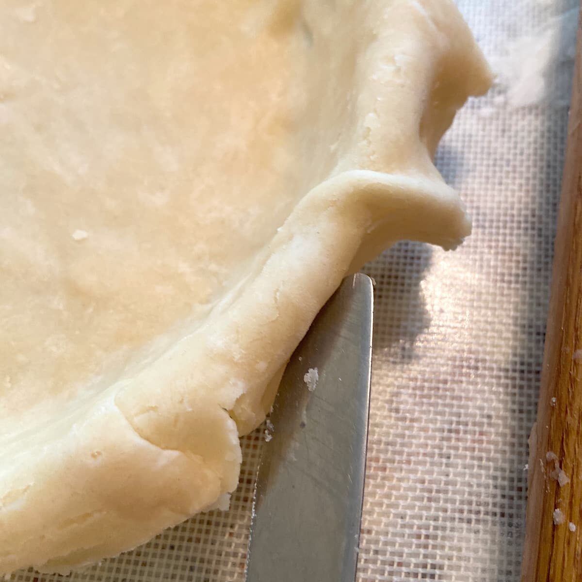 cutting away excess dough from edge