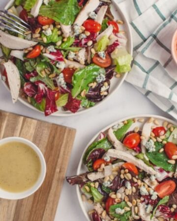 cup of tahini salad dressing with salads and pine nuts
