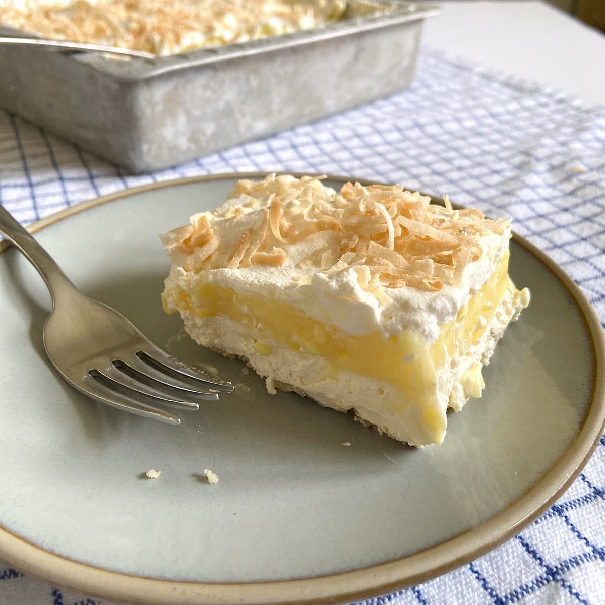 picture of a slice of coconut pudding dessert bar on a plate. 