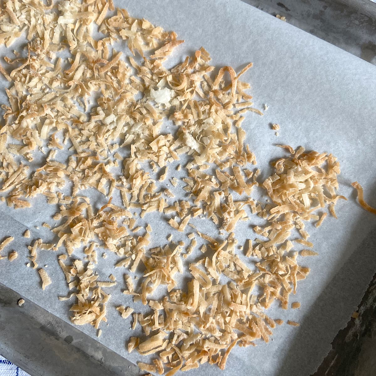 picture of toasted coconut on parchment paper on baking tray.