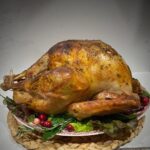 Golden roasted turkey on a platter of greens and cranberries