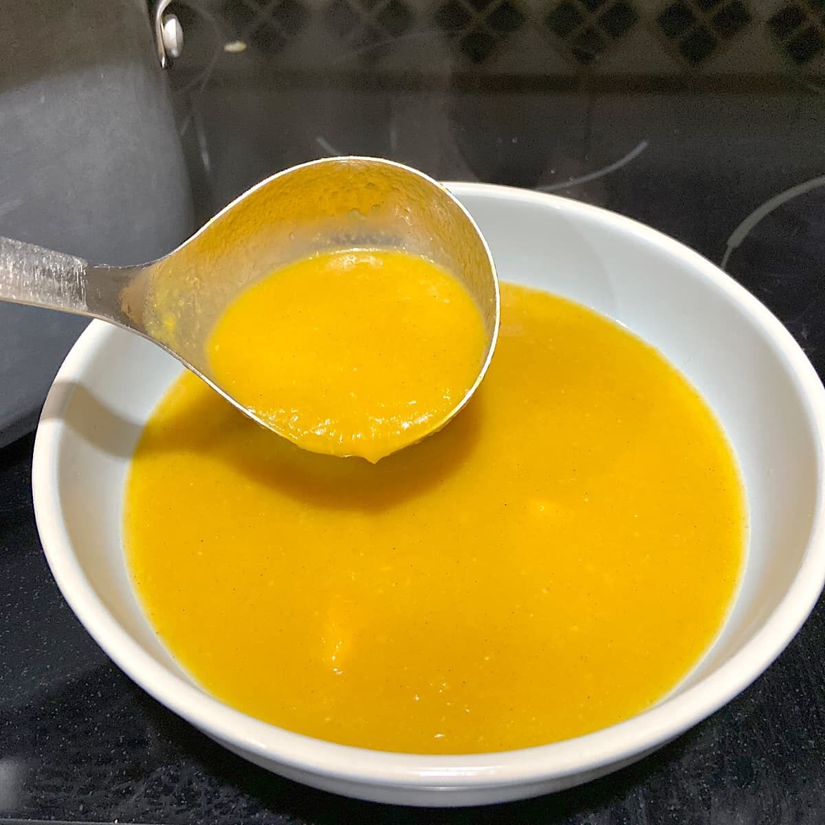 ladling acorn squash soup into bowl 