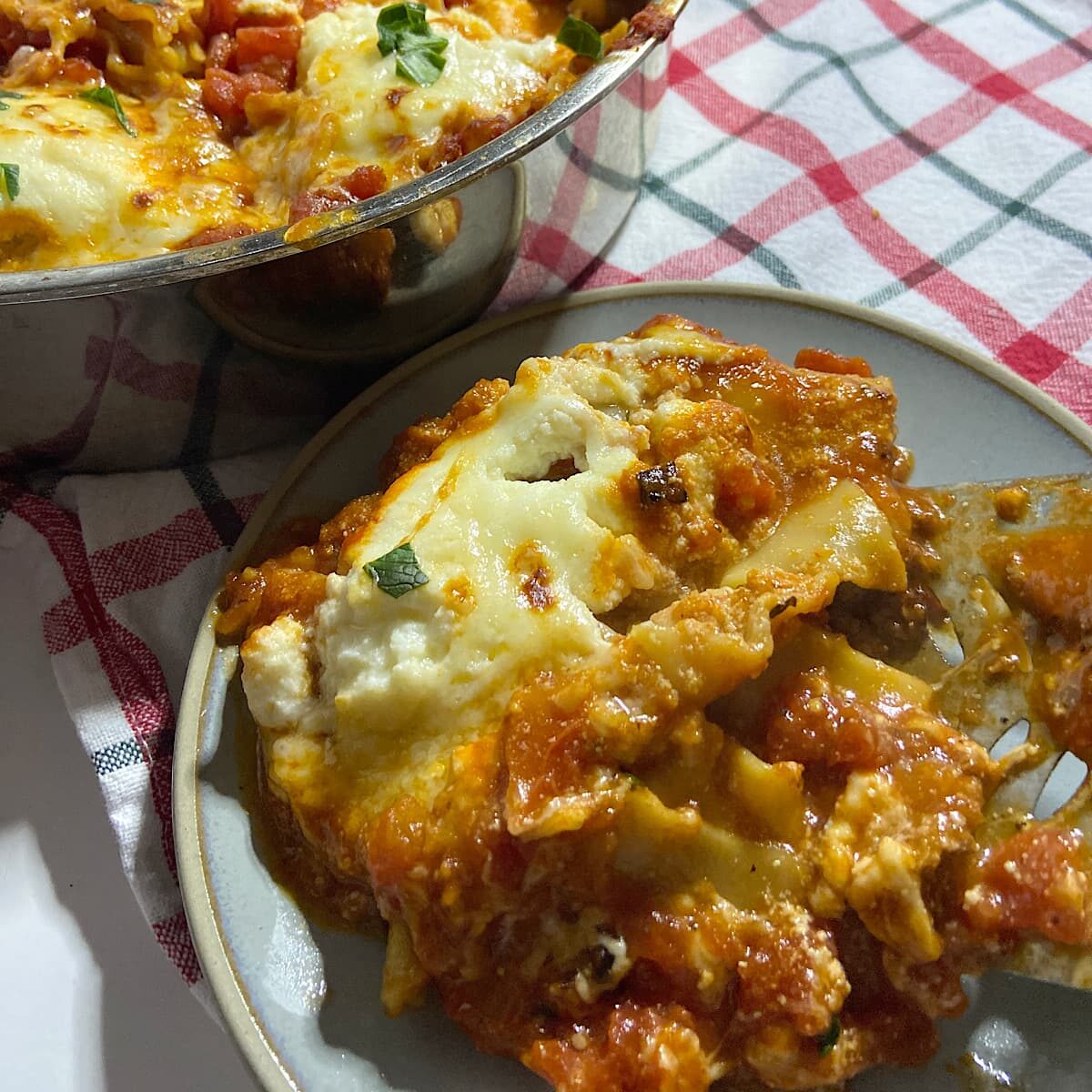 serving of stovetop lasagna on plate with skillet full in background