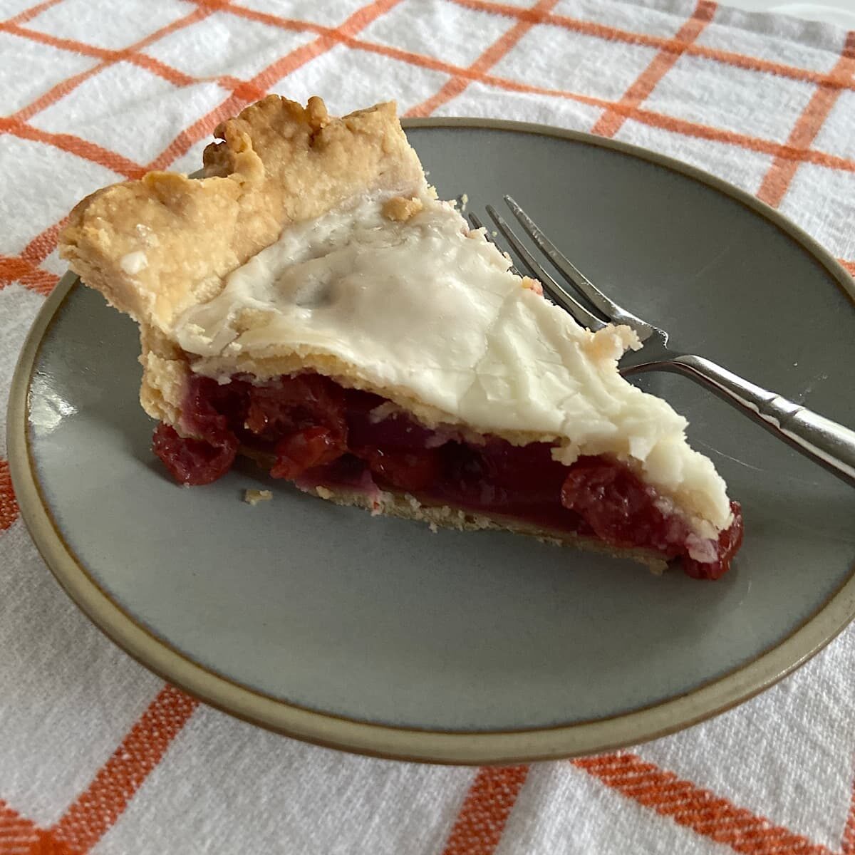slice of cherry pie on plate with a powdered sugar icing.