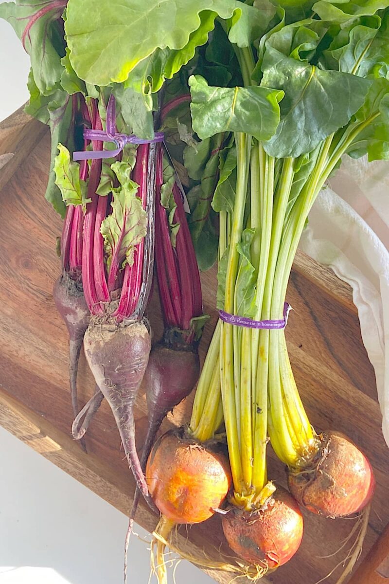 fresh red and golden beets on wooden tray
