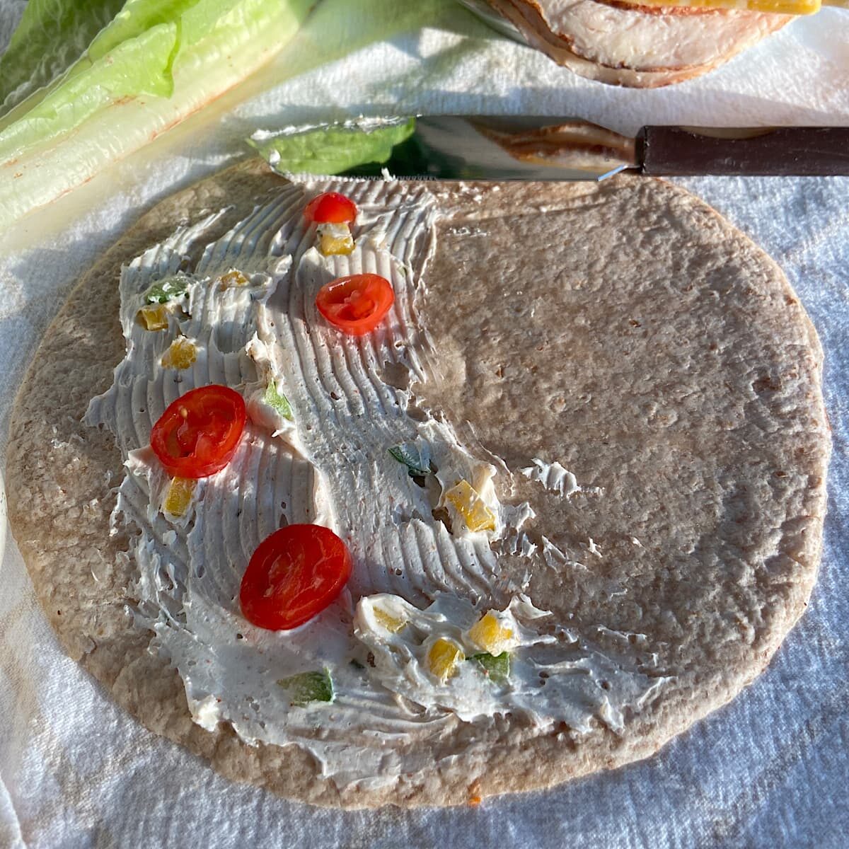 spread low-fat cream cheese over tortilla, sprinkle sliced tomatoes over cream cheese.