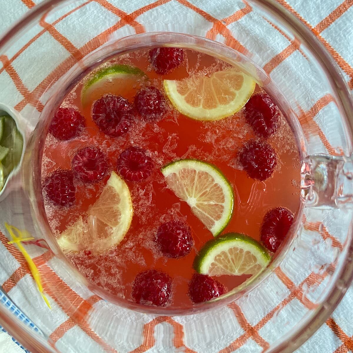 Top view of pitcher with cherry lemonade mocktail with lemon slices and raspberries.
