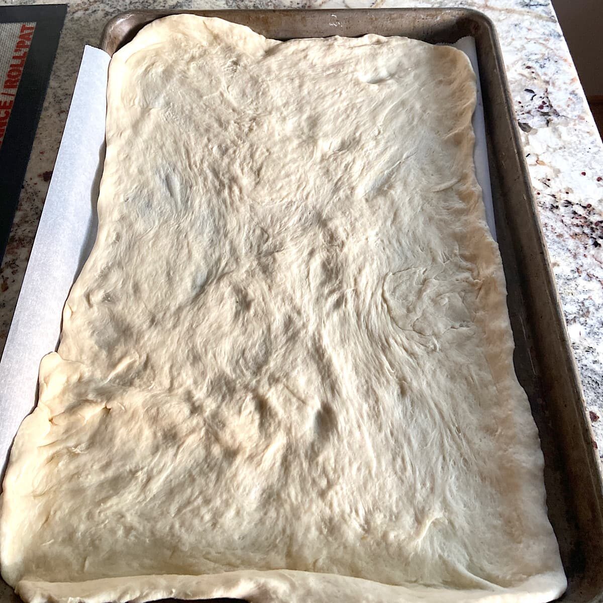 thin crust pizza Dough on parchment ready to bake