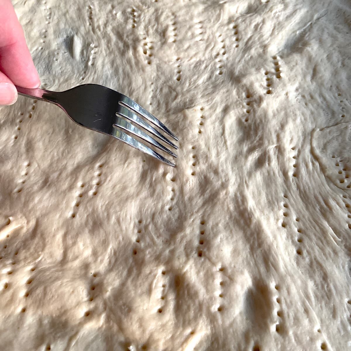 pierce thin crust pizza dough with a fork prior to prebaking