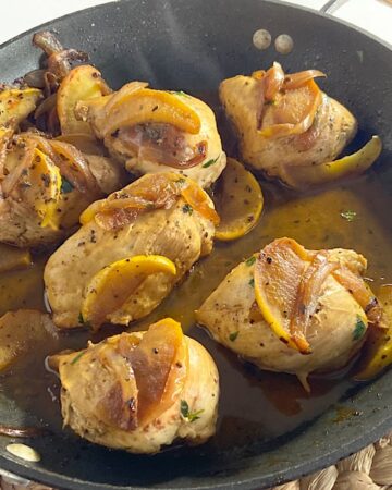 chicken with cooked apples and onions in pan.