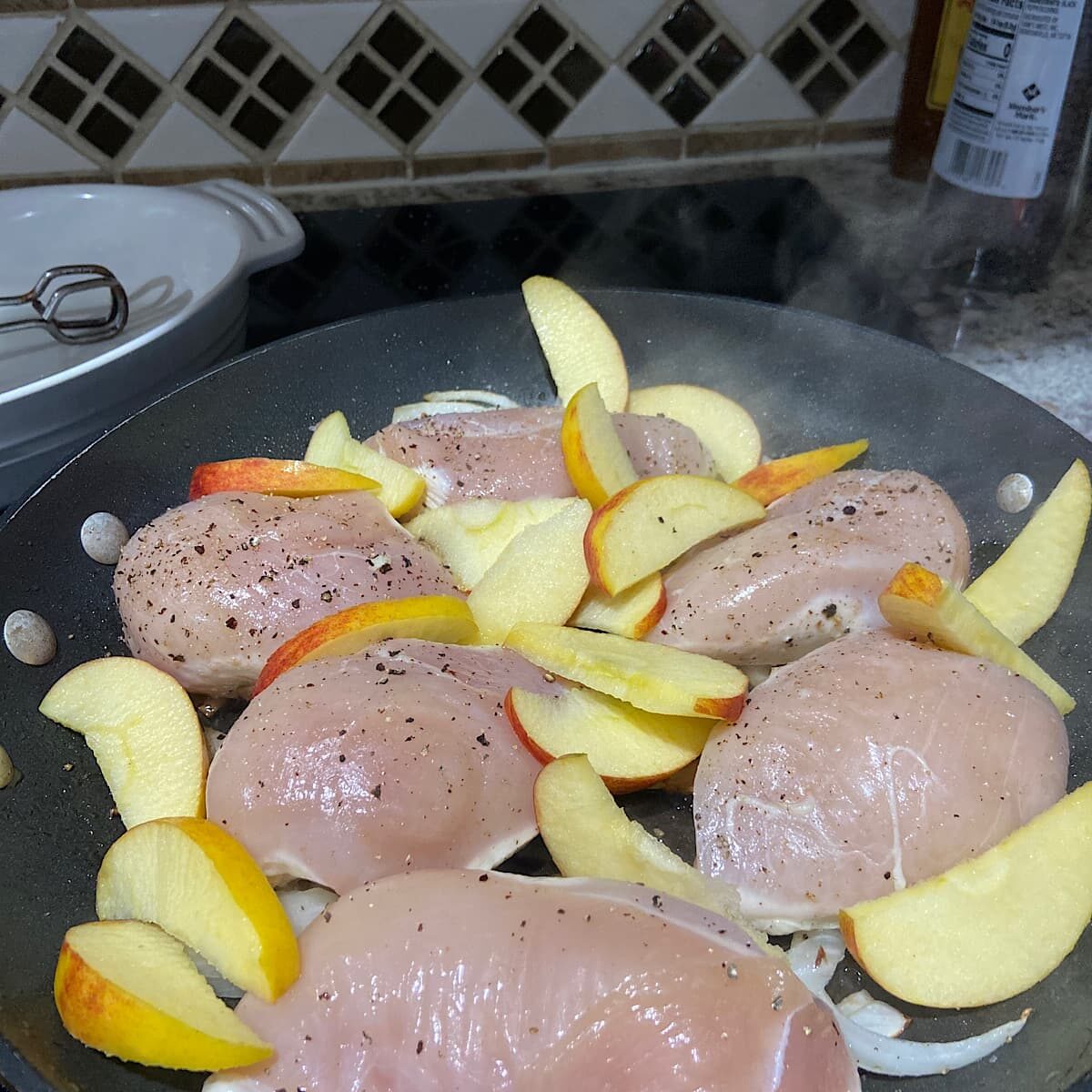 Pan with chicken, sliced apples, and onions. 