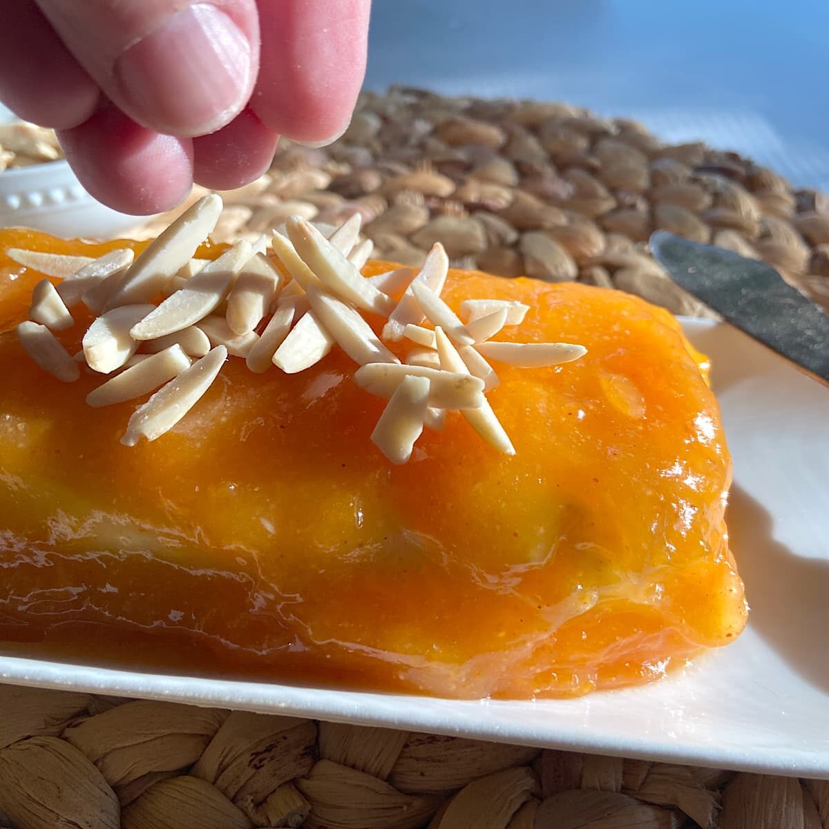 sprinkle toasted almonds on cream apricot glazed cream cheese log.