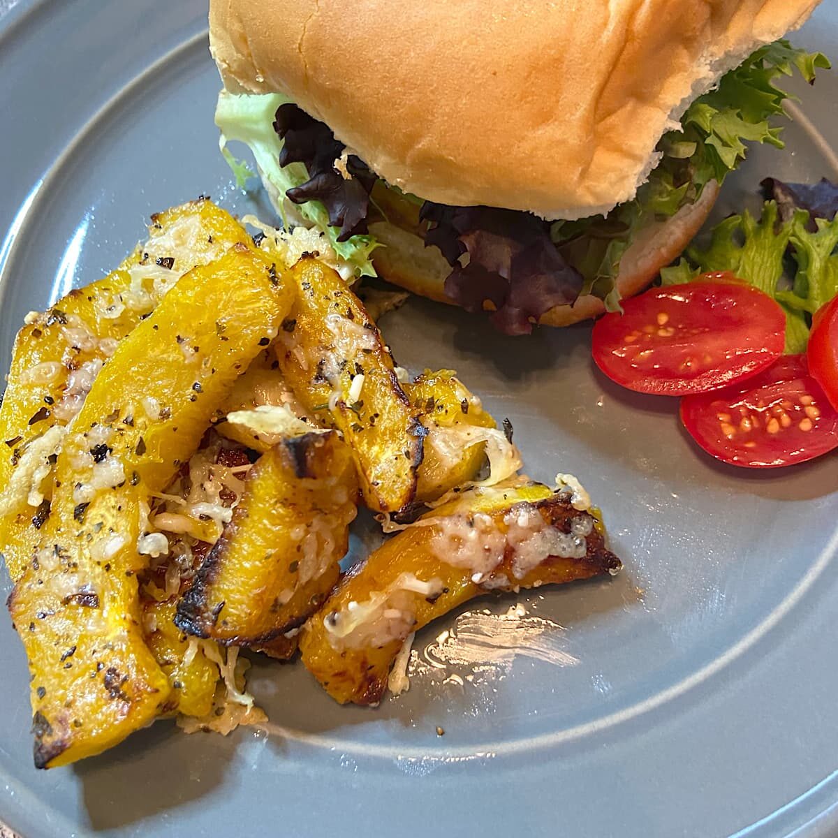 Roasted Squash on plate with burger, tomatoes, and lettuce. 