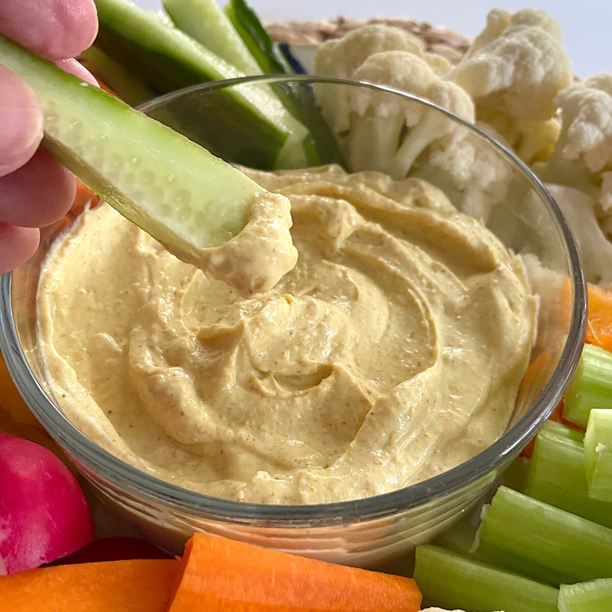 Close up picture of a bowl of curry dip with chopped vegetables.
