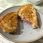 picture of a sliced Reuben sandwich on a plate.