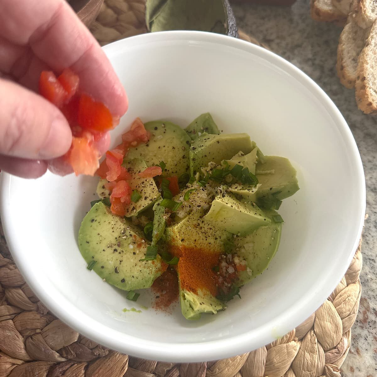 picture of chopped avocado, tomato, mined garlic, chopped green onion, and spices in a bowl.