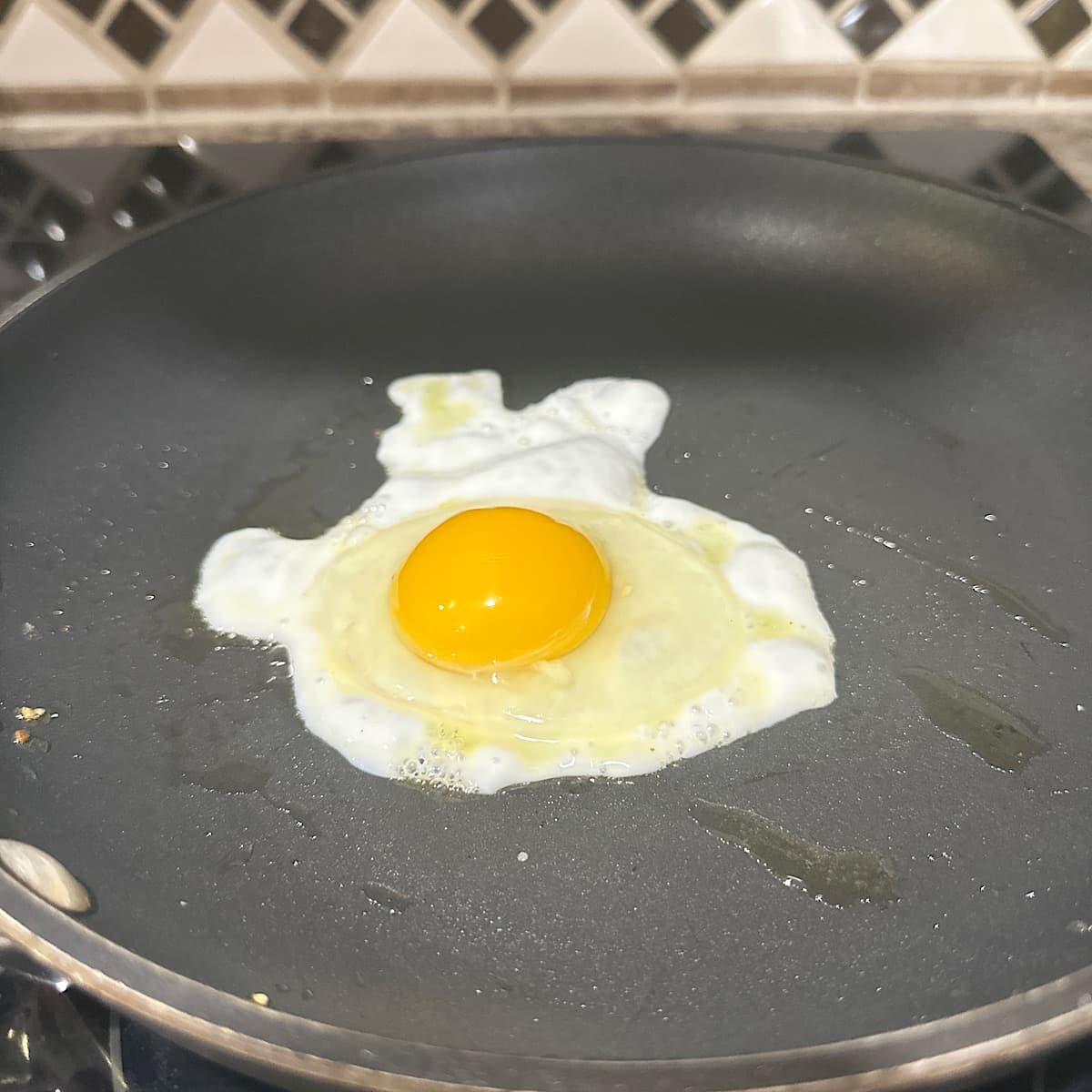 picture of egg cooking in evoo in pan.