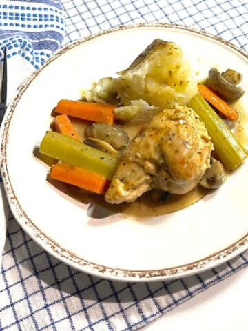plate of chicken in white wine sauce with vegetables.